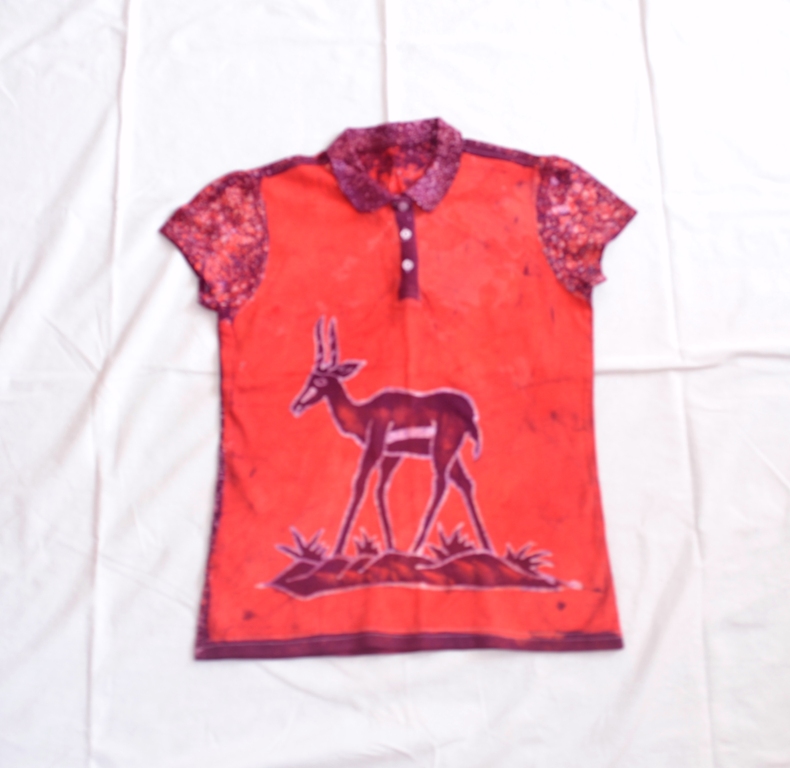 T-shirt batik for young girl. In front a gazelle stands on the bushes and  on the back uniform dotted lines, red. Slim, 61,5 x 41,5 cm. - Centre des  Hommes