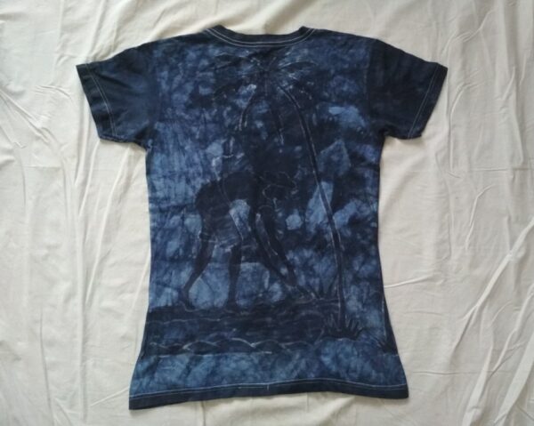 T-shirt batik for women. In front a lady carrying a baby on her back looking for the wood fire and in back a gentleman cultivates the land under a coconut tree; ash blue. 63 x 37 cm - Image 2
