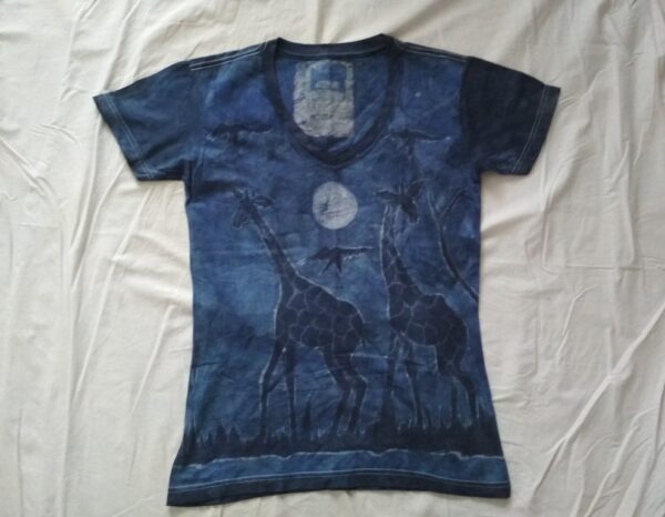 T-shirt batik for women. Two giraffes which in the middle of their neck the sun and in the back two giraffes that follow each other; light blue. 63 x 38 cm.